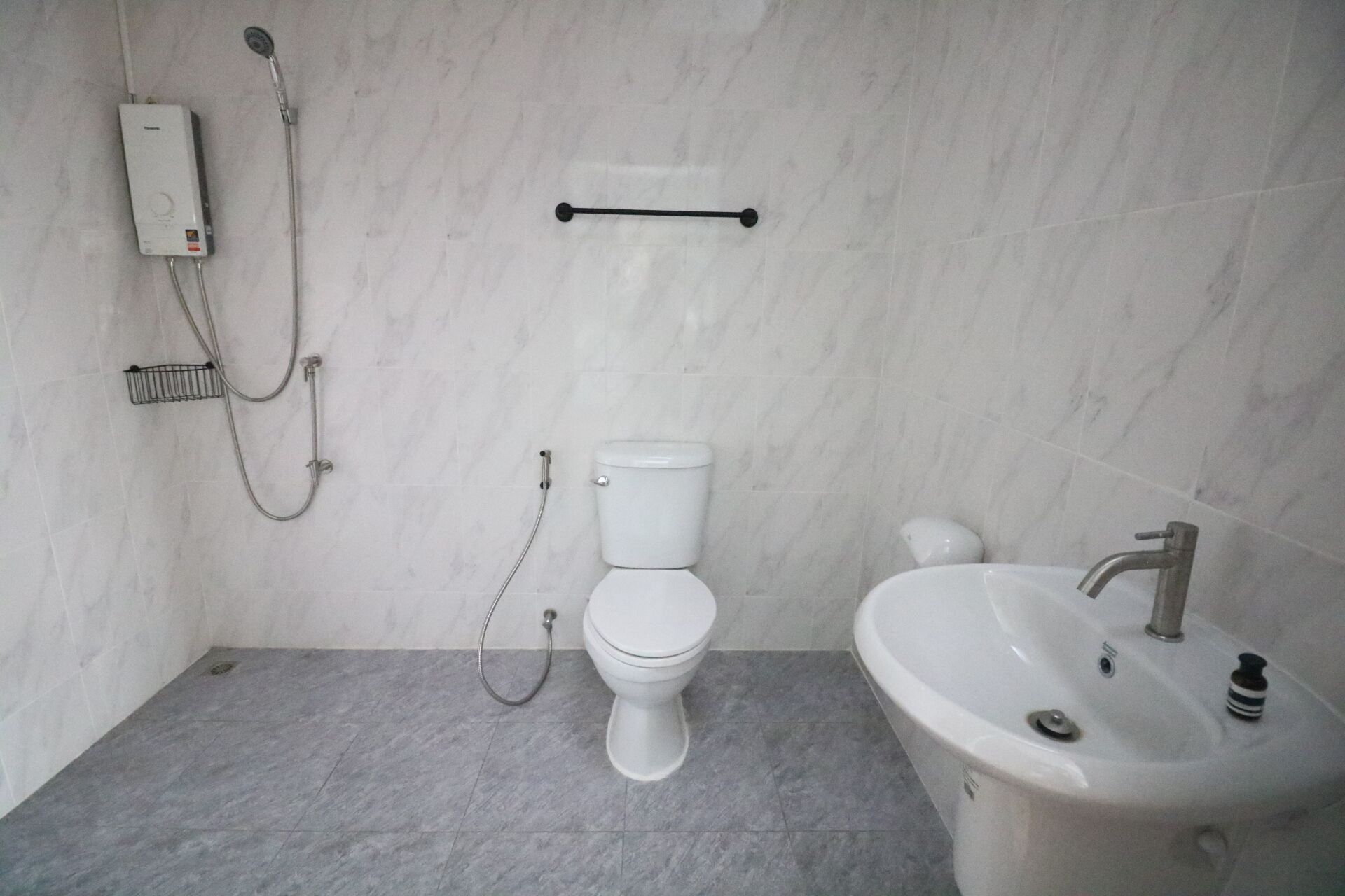 A bathroom with a toilet, a shower, and a sink.