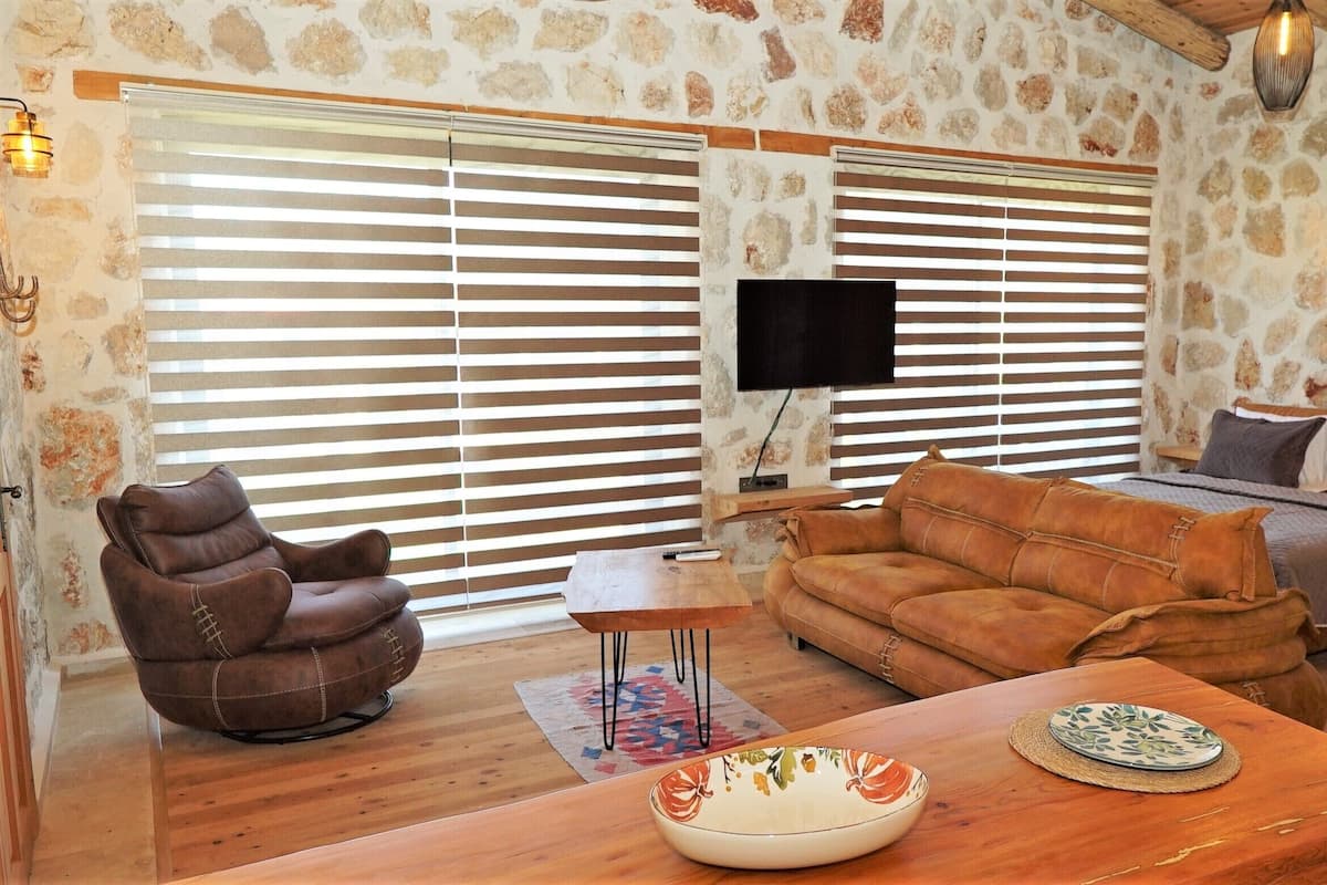 Un salon chaleureux avec un canapé en cuir marron, une table basse en bois et un téléviseur fixé au mur.