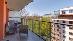 A balcony with wicker chairs and a view of neighboring buildings and trees. - Elegant Apartment on Salt Island | Parking | Balcony (Kolobrzeg)