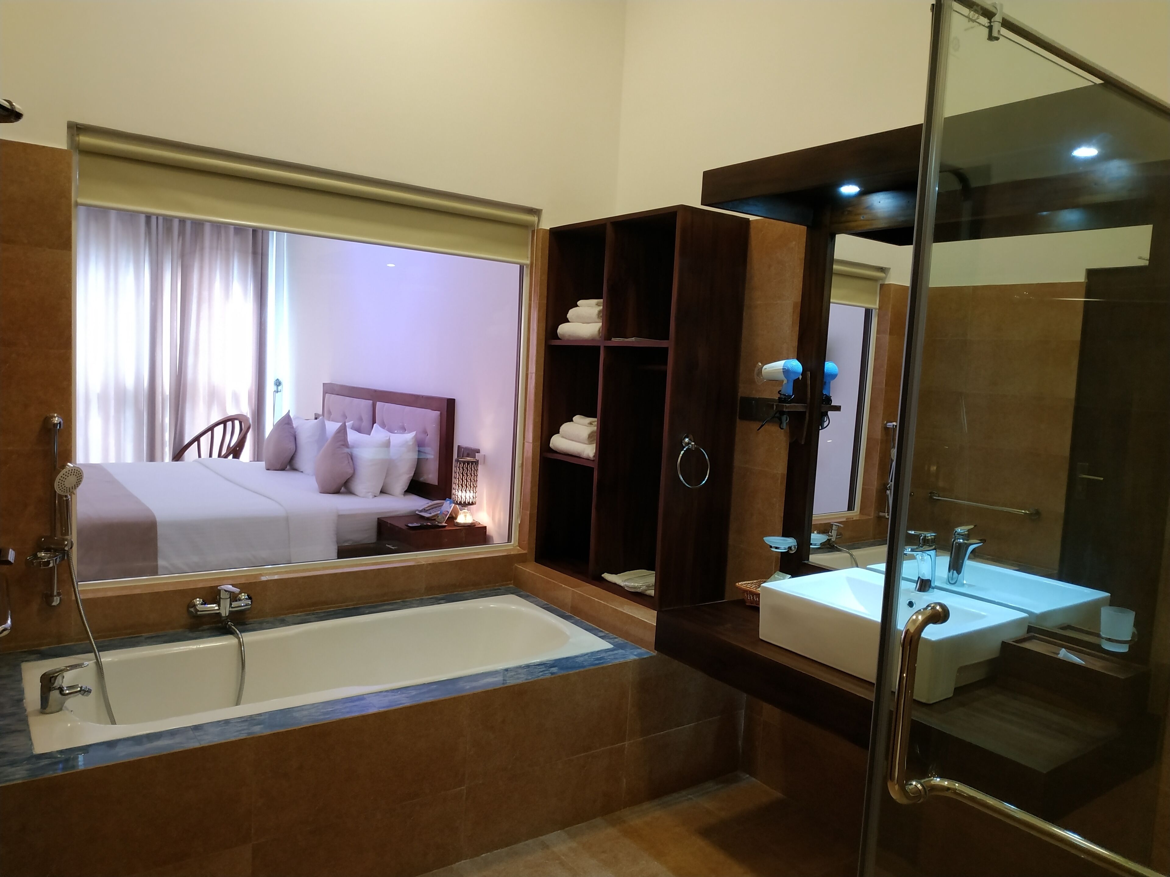 Un baño de hotel con una bañera grande, una zona de ducha separada, un tocador con lavabo y un espejo.