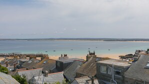 En kystby med trappeformede huse, der kigger ud over en sandstrand og et roligt hav.