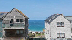 En kystbygning med balkon med udsigt over havet, en klar himmel og udsigt til stranden.