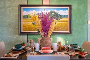 A dining table set with plates, bowls, and a vase of flowers.