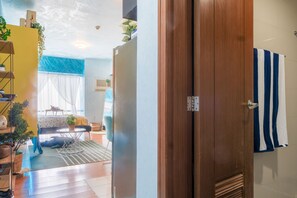 A room with a wooden door, a striped towel hanging on the wall, and a plant on the windowsill. - Eton Bay  (Manila)
