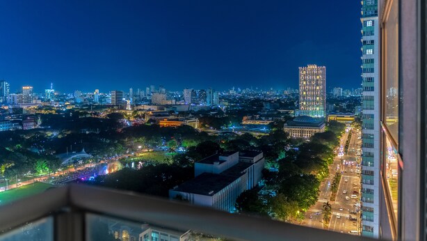 Un paisaje urbano nocturno con edificios iluminados y una calle concurrida.