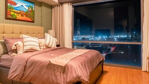 Un dormitorio con un ventanal grande, una cama con ropa de cama rosa y un cuadro en la pared.