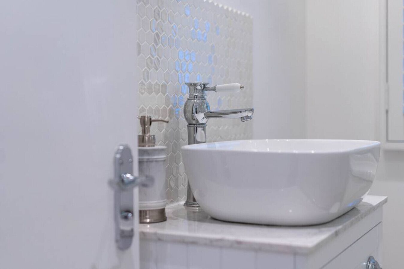 Une salle de bain avec un lavabo blanc, un robinet chromé et un distributeur de savon.