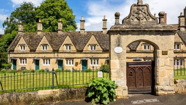 A traditional stone building with a symmetrical facade, multiple chimneys, and a gated entrance. - Windsor Cottage - Bolthole in the heart of CN (Chipping Norton)