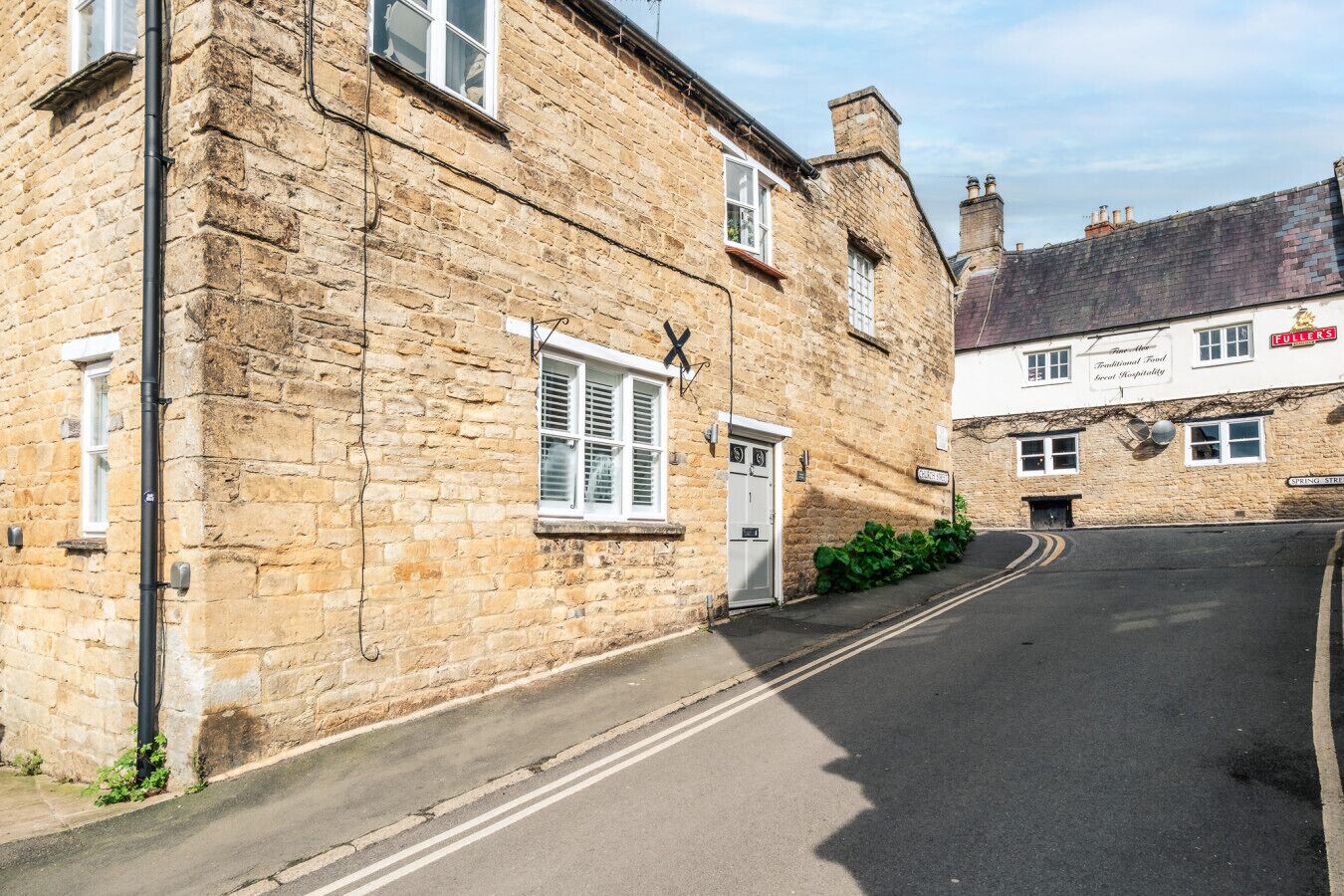 A stone building with a traditional design, a sign for a pub, and a clear road.