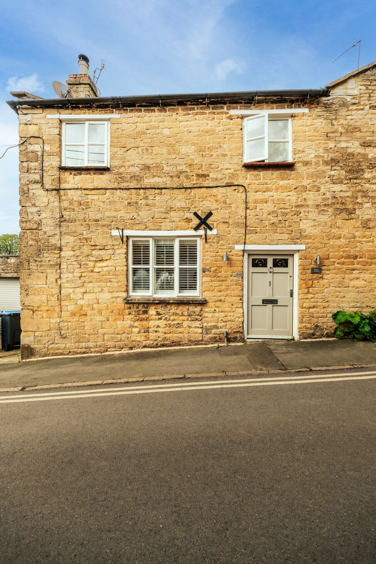 A stone building with a white door, a window with shutters, and a satellite dish.