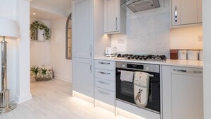 Une cuisine moderne avec des meubles blancs, une cuisinière à gaz et un four encastré.