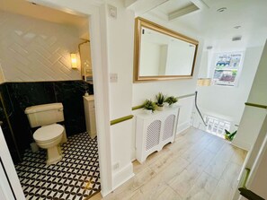 Ein Badezimmer mit Toilette, Waschbecken und Spiegel. Eine Treppe führt zu einer anderen Etage.