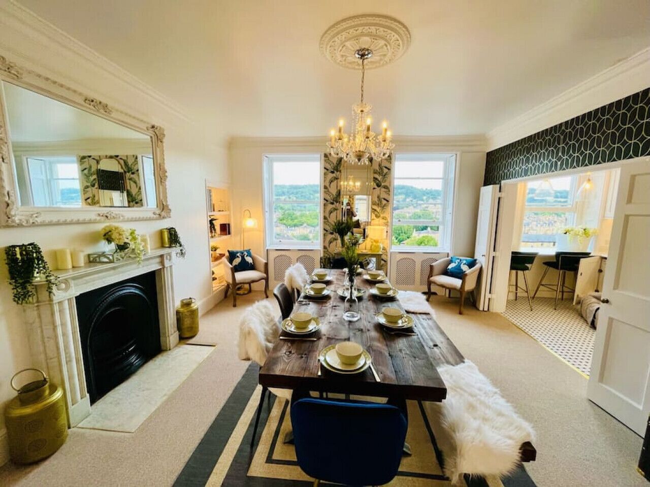 Une salle à manger avec une longue table dressée pour six personnes, une cheminée et une vue sur l’extérieur.