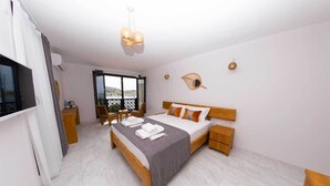 A bedroom with a bed, bedside tables, a TV, a window, and a view of the outside. - Foça Kybele (Foça)