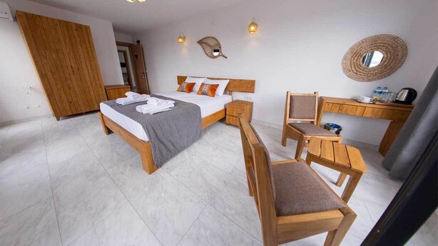 A bedroom with a bed, bedside tables, a desk, and a chair. - Foça Kybele (Foça)