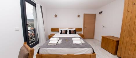 Un dormitorio con cama de madera, puerta al balcón, armario y una mesita de noche de madera.