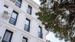 A multi-story building with white exterior walls, black window frames, and decorative balconies. - Foça Kybele (Foça)