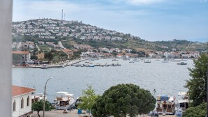 A coastal town with a marina, buildings on a hillside, and a clear sky. - Foça Kybele (Foça)