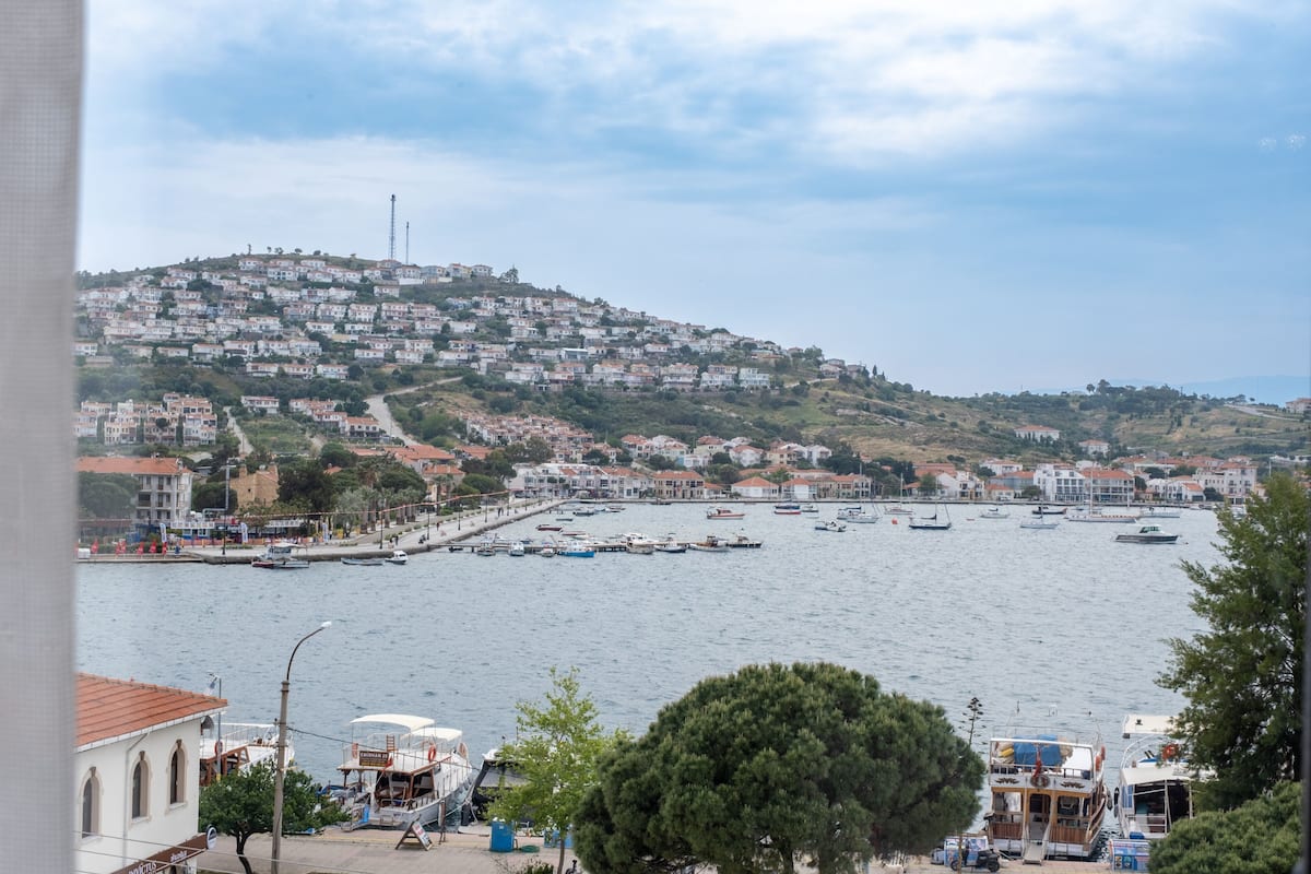 A coastal town with a marina, buildings on a hillside, and a clear sky.