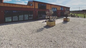 Een modern gebouw met een grindpleintje, grote ramen en terrasplekken buiten.