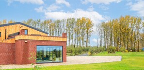 Een modern huis met een bakstenen gevel, grote glasramen en een houten dak.