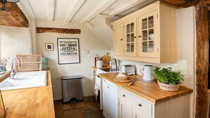 Una cocina con vigas de madera, un lavabo, una estufa y armarios.