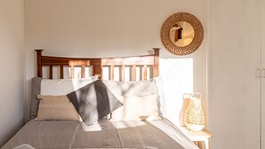 A bed with a wooden headboard, multiple pillows, a quilted blanket, and a bedside table with a lantern. - Modern 2 BD w Garden in the Heart of Tetbury (Tetbury)