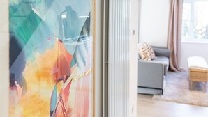A modern living room with a grey sofa, a small wooden table, and a window with curtains. - Modern 2 BD w Garden in the Heart of Tetbury (Tetbury)