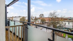 A balcony with a view of a cityscape, including buildings and a church spire.
