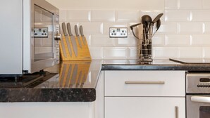 A kitchen with a microwave, knife block, and utensils on the counter.