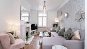 Een moderne woonkamer met een open haard, een bank en een televisie.