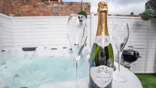 Champagnefles en twee glazen op een tafel in de buurt van een jacuzzi.