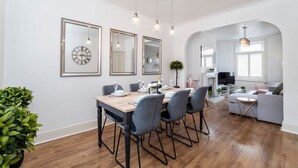 Een moderne eethoek met een houten tafel, vier stoelen en een grote spiegel.