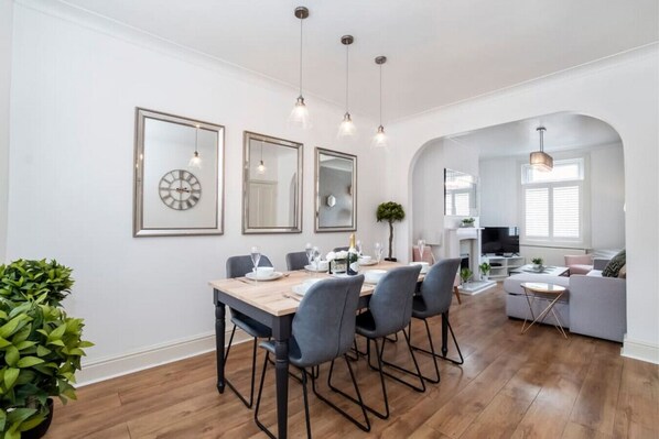 A modern dining area with a wooden table, four chairs, and a large mirror.