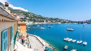 A coastal town with a marina filled with boats, a clear blue sky, and buildings with traditional architecture. - MAISON BLEUE AP4362 By Riviera Holiday Homes (Villefranche-sur-Mer)