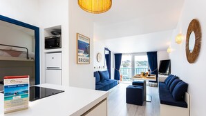 A modern hotel room with a kitchenette, a dining area, a sofa, and a view of the city. - MAISON BLEUE AP4362 By Riviera Holiday Homes (Villefranche-sur-Mer)