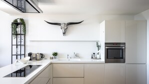 A modern kitchen with white cabinetry, a built-in oven, a black and white backsplash, and a cow skull decoration.