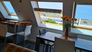 A modern room with skylights, a dining area, and a view of the sea.