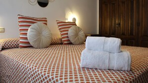 A neatly made bed with patterned bedding, two pillows, and a stack of towels. - Casa Hemingway - Marbella Old Town (Marbella)