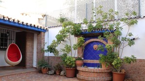 A courtyard with a hanging chair, potted plants, and a blue-tiled fountain. - Casa Hemingway - Marbella Old Town (Marbella)