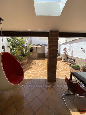 A patio with a hanging chair, a grill, and potted plants. - Casa Hemingway - Marbella Old Town (Marbella)