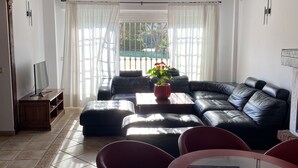 A living room with a black leather sofa, a glass coffee table, and red chairs. There is a potted plant on the coffee table. - Casa Hemingway - Marbella Old Town (Marbella)