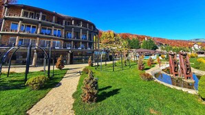 Ein mehrstöckiges Hotel mit Gartenanlage, inklusive Teich und Spazierwegen.