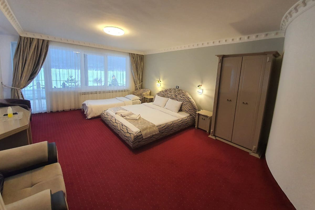 A hotel room with a large bed, two bedside tables, a desk, and a wardrobe.