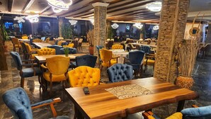 Ein Restaurant mit mehreren Tischen und Stühlen, wobei die Stühle eine Mischung aus gelber und blauer Polsterung aufweisen.