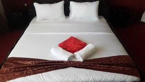 Ein ordentlich bezogenes Bett mit weißer und roter Bettw äsche, einem braunen Zierlaufschuh und zwei weißen Kissen.