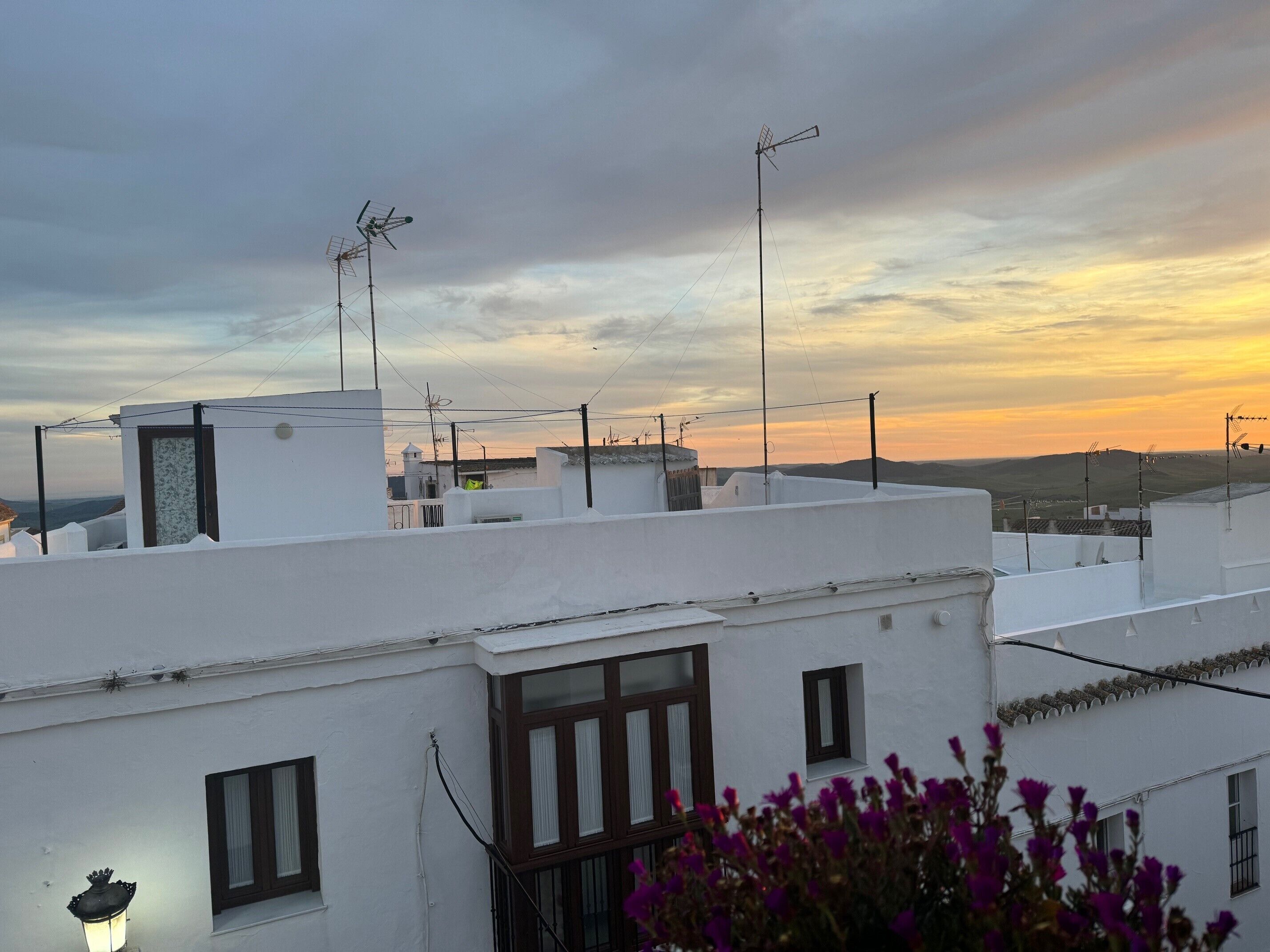 A rooftop with white buildings, multiple antennas, and a clear sky.