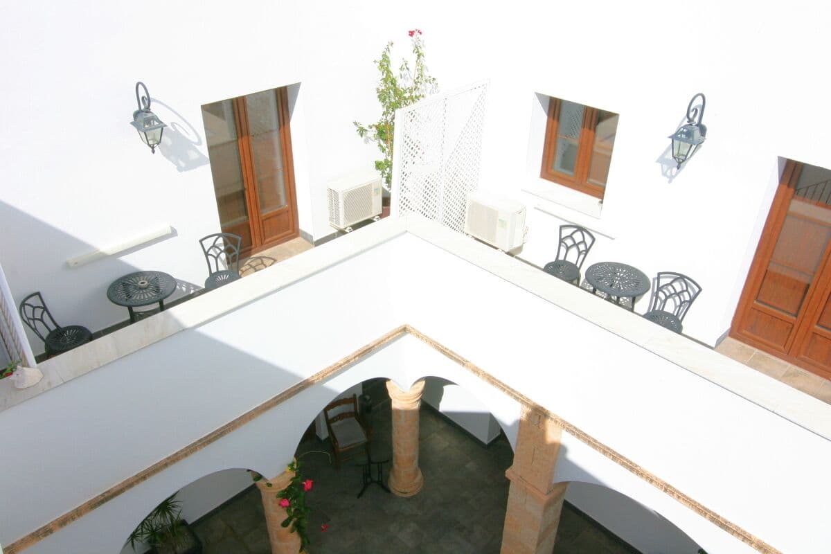 A courtyard with a central column, two tables, and chairs. There are two air conditioning units and a plant in the center.