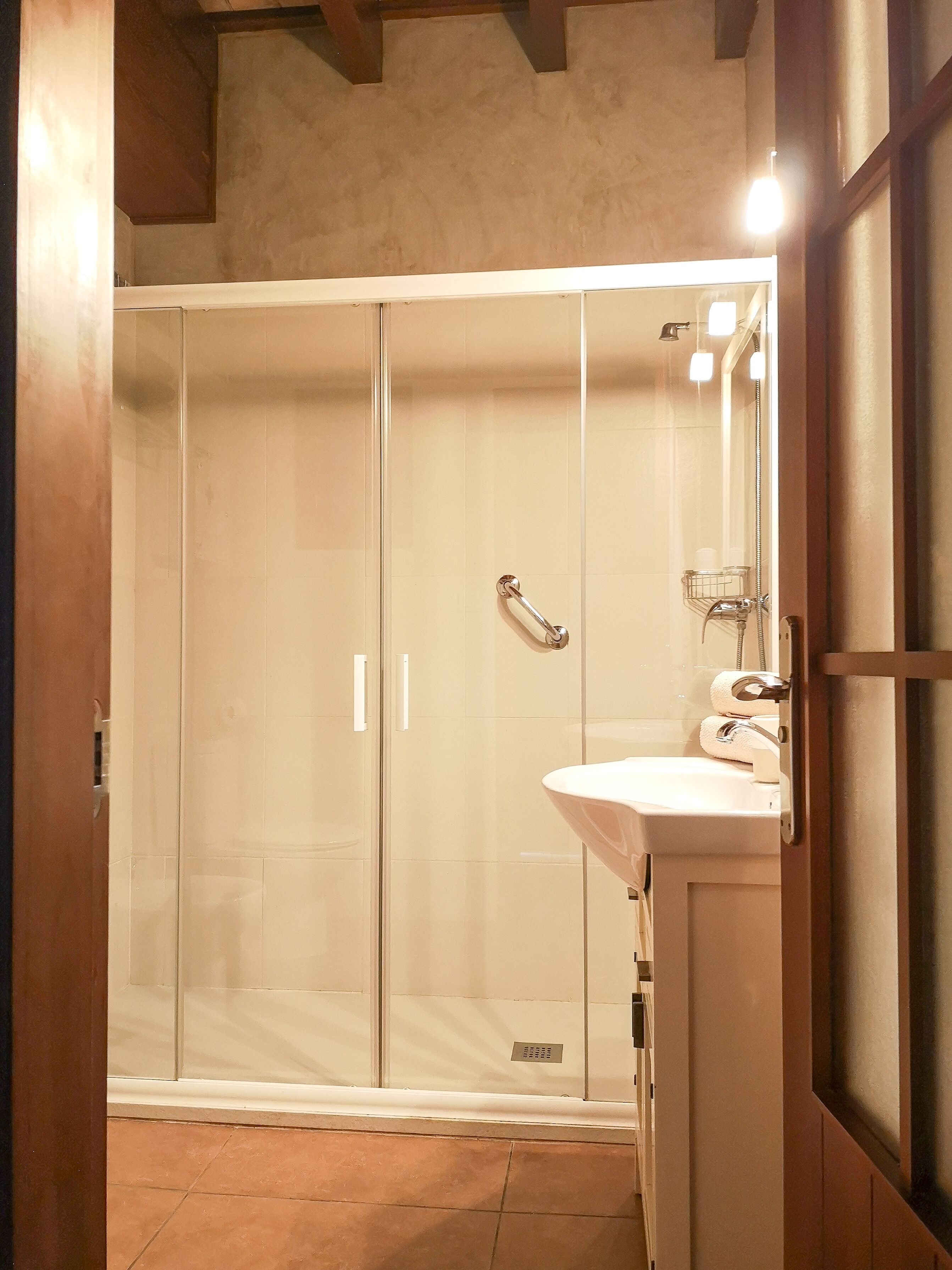 A modern bathroom with a glass-enclosed shower, a white sink, and a mirror.