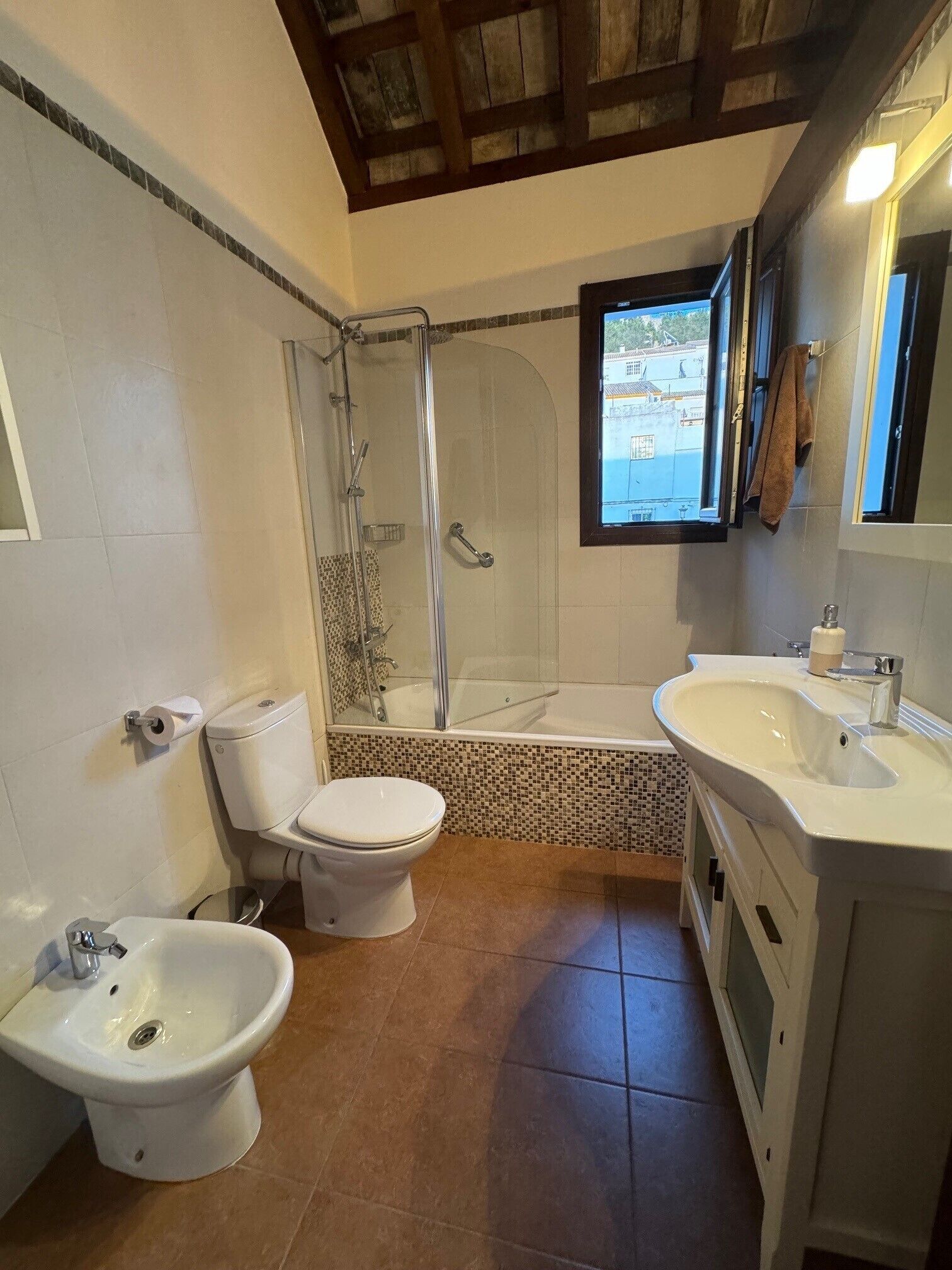 A bathroom with a shower, toilet, bidet, and sink.